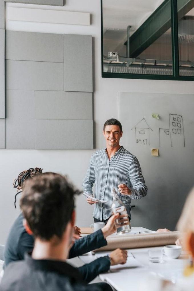 a man giving an explanation in a meeting room to colleagues